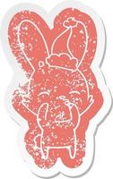 curious bunny cartoon distressed sticker of a wearing santa hat vector