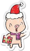 happy distressed sticker cartoon of a pig with xmas present wearing santa hat