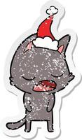 talking cat distressed sticker cartoon of a wearing santa hat vector