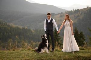 happy stylish bride and groom running and having fun in mountains on summer sunny day photo