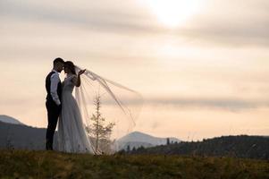 happy stylish bride and groom running and having fun in mountains on summer sunny day photo