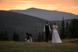 happy stylish bride and groom running and having fun in mountains on summer sunny day photo