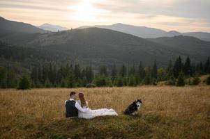 happy stylish bride and groom running and having fun in mountains on summer sunny day photo