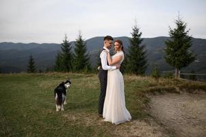 happy stylish bride and groom running and having fun in mountains on summer sunny day photo
