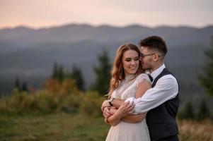 happy stylish bride and groom running and having fun in mountains on summer sunny day photo