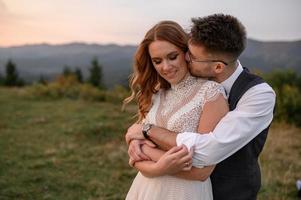 happy stylish bride and groom running and having fun in mountains on summer sunny day photo