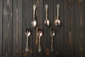 Six old silver spoons on a rustic wooden background. photo