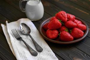 A bowl of red juicy strawberries on rustic wooden table. Healthy and diet snack food concept. photo