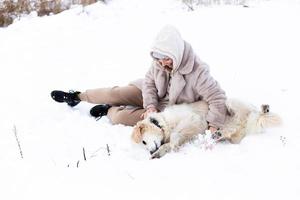 Young beautiful woman and her golden retriever dog having fun in winter. photo