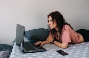 Woman working with laptop and lying on couch. Freelancing and work from home. photo