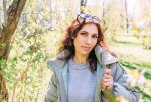 Portrait of a young brunette woman in spring in a park in outerwear. photo