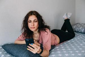 A young brunette woman is resting at home and talking on a smartphone photo