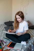 The girl after school plays at home, draws with pencils and felt-tip pens photo