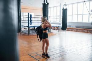 Training is over, time to go home. Adult female with black bag and headphones in the gym photo