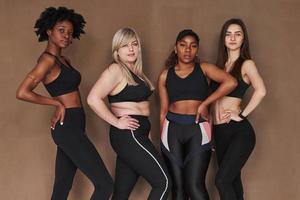 Results of workout. Group of multi ethnic women standing in the studio against brown background photo