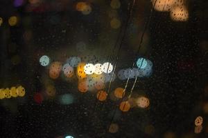 gotas de agua en la ventana con fondo de luz bokeh de la vista nocturna de la ciudad foto