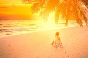 young female sitting on tropical beach and relaxing at summer time photo