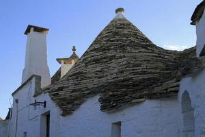 The characteristic Trulli in Alberobello, Italy, against a blue sky photo