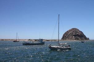 barcos que yacen ociosamente en morro bay, con morro rock en el fondo. foto