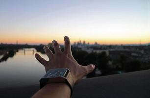 Hand reaching out to the horizon during dusk photo