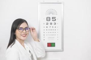 Young ophthalmologist doing visual test for customer using eye chart in optical center, eyecare concept. photo