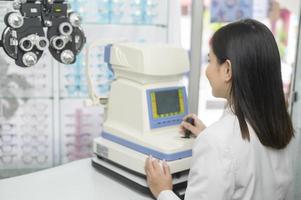 joven oftalmólogo haciendo una prueba visual para el cliente usando autorrefractor en el centro óptico, concepto de cuidado de los ojos. foto