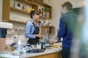 joven barista con mentalidad de servicio con el cliente en la cafetería foto