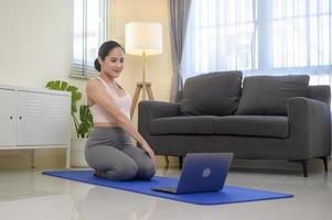 Fit young woman practicing yoga at home via online class with professional instructor, sport and healthy lifestyle concept. photo