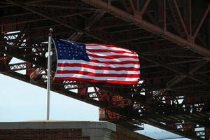 bandera estadounidense ondeando en el viento junto al puente golden gate en san francisco, california foto