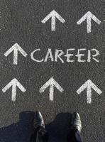 Moving forward - A man choosing his next career steps, looking down at multiple arrows and the word career written on the floor photo