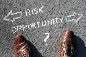 Top view on a man standing in front of the words Risk and Opportunity with arrows pointing to the left and right side of the picture photo