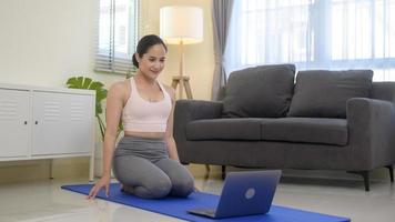 Fit young woman practicing yoga at home via online class with professional instructor, sport and healthy lifestyle concept. photo