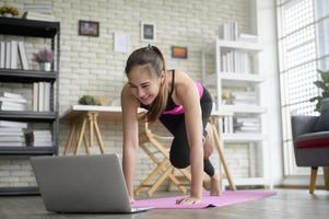 Fit young woman practicing yoga at home via online class with professional instructor, sport and healthy lifestyle concept. photo