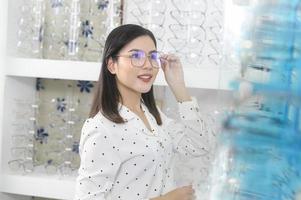 Young female customer choosing glasses in optical center, Eyecare concept. photo