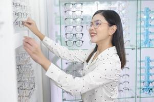 Young female customer choosing glasses in optical center, Eyecare concept. photo