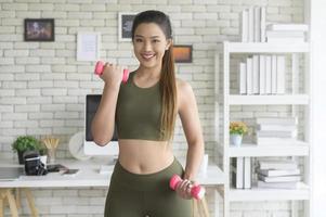 Young fitness woman in sportswear lifting dumbbells at home, Healthy and Lifestyles. photo