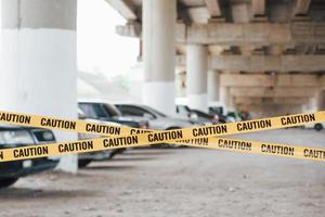 territorio prohibido. cinta amarilla de precaución cerca del estacionamiento de autos durante el día. escena del crimen foto