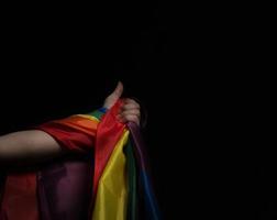 bandera del orgullo lgbtq sobre fondo negro. bandera del arco iris lgbt en mano gay. foto