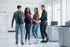 Supporting each other. Group of young people walking in the office at their break time photo