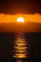 close up big Sun set, Sunrise with the cloud and mountain layer at the sea., Thailand. photo