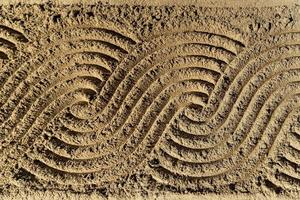 Continuous curve wave pattern art on the sand background. photo