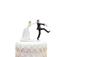 groom doll and statue is running away but bride can catch him finally. the funny wedding story doll on the top of cake with isolated object on white background and clipping path. photo