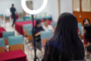 audience and participant listen to teacher and lecturer at the front of stage about women face make up. photo