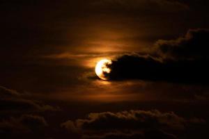 cierra el sol con una nube frente a él en el crepúsculo del atardecer. foto