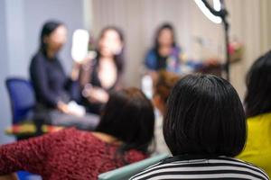 audience and participant listen to teacher and lecturer at the front of stage about women face make up. photo