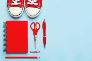 Top view of red sneakers and red school supplies with space for tex. Back to school concept photo