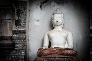 gran estatua blanca de buda con una antigua pared de fondo. foto