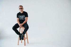 sonriendo a la cámara. hombre positivo con ropa informal se divierte en el estudio contra la pared blanca foto