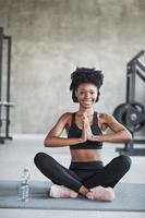 Yoga exercises. African american woman with curly hair and in sportive clothes have fitness day in the gym photo