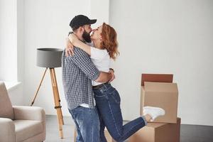 Chair and boxes near them. Happy couple together in their new house. Conception of moving photo